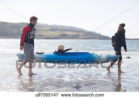 Stock Photo - Parents carrying son in canoe on beach, Loch Eishort, Isle of Skye, Hebrides, Scotland. Fotosearch