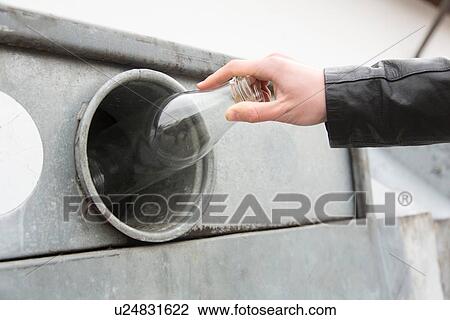 Stock Image - Person recycling milk bottle in bottle bank. Fotosearch