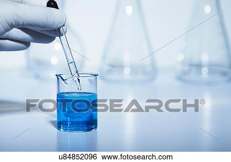 Stock Photograph - Pipetting sodium carbonate to copper (II) sulfate. Both solutions 0. 5 M concentration. Copper (II) carbonate precipitate formed result: CuSO4 + Na2CO3 -> CuCO3 + Na2SO4. Double displacement reaction. Fotosearch