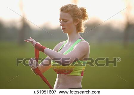 Stock Photo - Portrait of a woman applying hand straps for boxing gloves in the park. Fotosearch