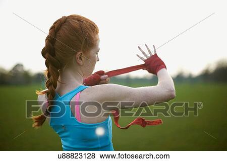 Portrait of a woman putting on boxing gloves straps in the park View Large Photo Image Stock Photo - Portrait of a woman putting on boxing gloves straps in the park. Fotosearch