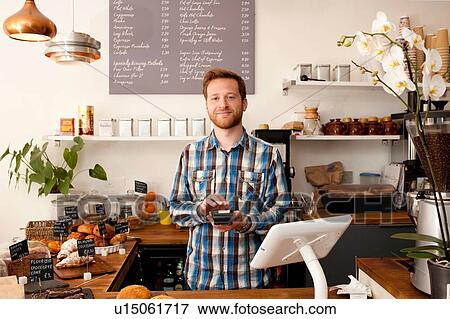 Portrait of cafe waiter with card machine behind counter View Large Photo Image Stock Photo - Portrait of cafe waiter with card machine behind counter. Fotosearch