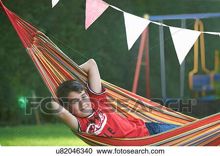 Portrait of confident boy reclining in striped garden hammock with hands behind head View Large Photo Image Stock Image - Portrait of confident boy reclining in striped garden hammock with hands behind head. Fotosearch