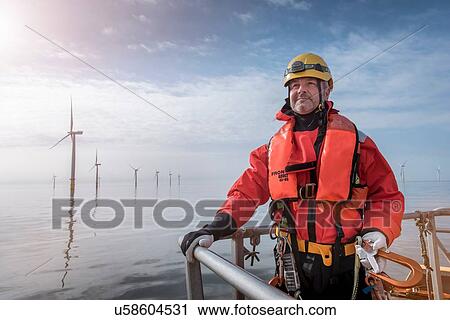 Stock Image - Portrait of engineer on boat at offshore windfarm. Fotosearch