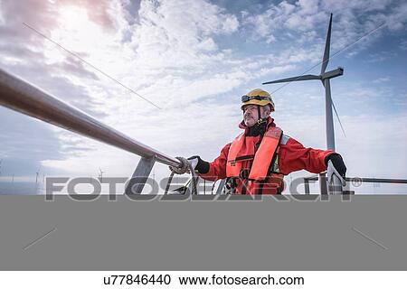 Stock Image - Portrait of engineer on boat at offshore windfarm. Fotosearch