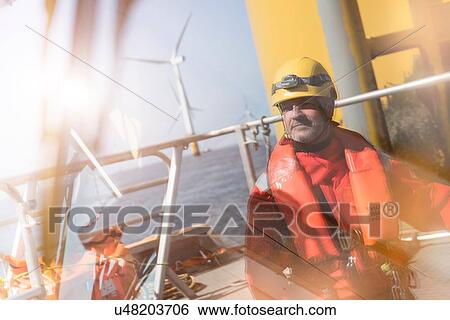 Stock Photograph - Portrait of engineer reflected in windscreen of service boat at offshore windfarm. Fotosearch