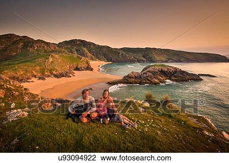 Stock Image - Portrait of family sitting on hillside, Murder hole beach, Melmor Head, Ireland. Fotosearch