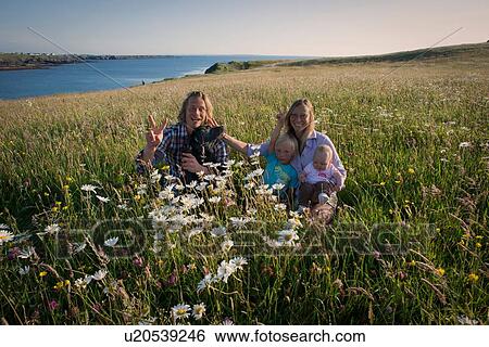 Stock Photograph - Portrait of family sitting on hillside, White strand, County Clare, Ireland. Fotosearch