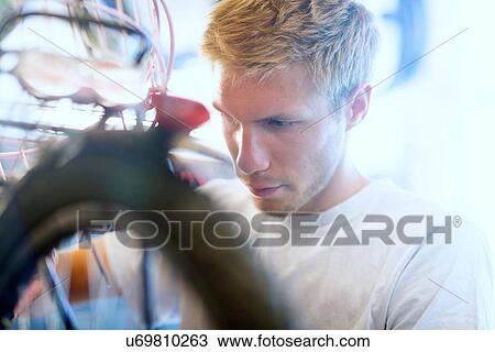 Stock Image - Portrait of mid adult man repairing bicycle. Fotosearch