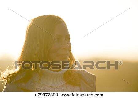 Stock Image - Portrait of mid adult woman at sunset. Fotosearch