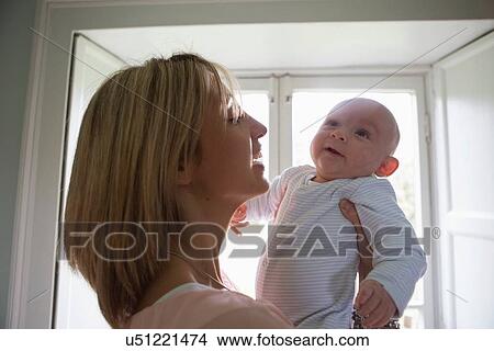 Picture - Portrait of smiling mother holding new baby boy. Fotosearch