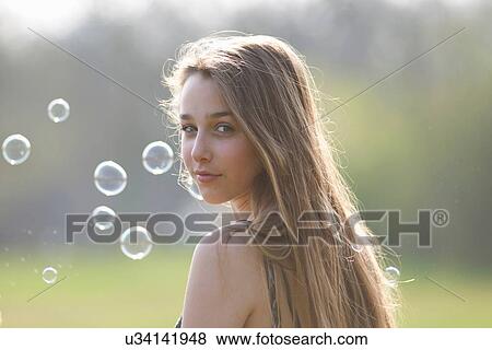 Portrait of teenage girl looking over her shoulder in park View Large Photo Image Stock Photo - Portrait of teenage girl looking over her shoulder in park. Fotosearch