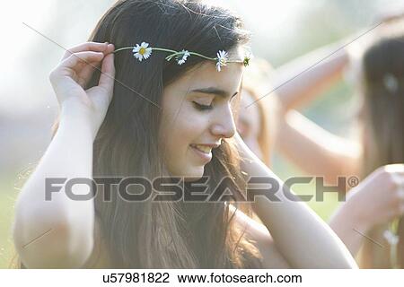 Portrait of teenage girl putting on daisy chain headdress in park View Large Photo Image Stock Image - Portrait of teenage girl putting on daisy chain headdress in park. Fotosearch