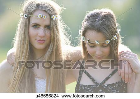 Picture - Portrait of teenage girls wearing daisy chain headdresses in park. Fotosearch