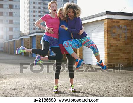 Stock Image - Portrait of three women wearing sports clothing jumping. Fotosearch
