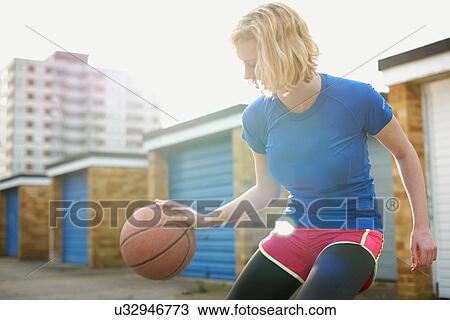 Stock Image - Portrait of woman bouncing basketball. Fotosearch