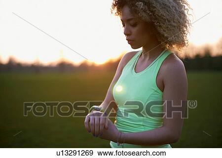 Portrait of woman checking watch after exercise in the park View Large Photo Image Stock Photo - Portrait of woman checking watch after exercise in the park. Fotosearch