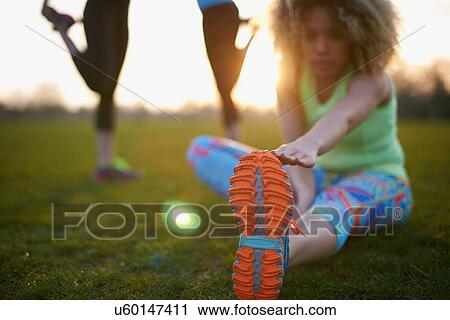 Stock Image - Portrait of woman stretching before exercise in park. Fotosearch