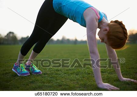 Stock Image - Portrait of woman warming up to exercise in the park. Fotosearch