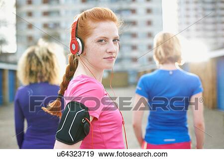 Portrait of woman wearing armband and headphones before exercise looking over shoulder at camera View Large Photo Image Stock Photo - Portrait of woman wearing armband and headphones before exercise looking over shoulder at camera. Fotosearch