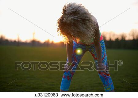 Stock Image - Portrait of woman winding down after exercise in park. Fotosearch
