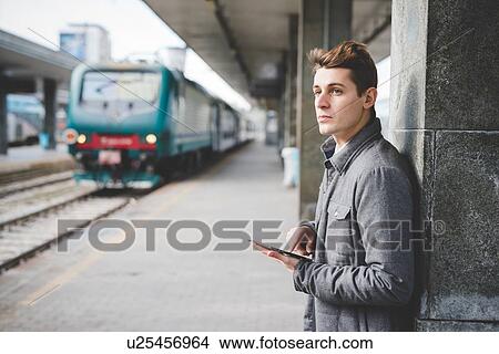 Portrait of young businessman commuter using digital tablet at train station. View Large Photo Image Picture - Portrait of young businessman commuter using digital tablet at train station.. Fotosearch