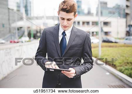 Portrait of young businessman commuter using digital tablet. View Large Photo Image Picture - Portrait of young businessman commuter using digital tablet.. Fotosearch