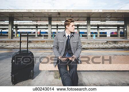 Portrait of young businessman commuter using digital tablet at train station. View Large Photo Image Picture - Portrait of young businessman commuter using digital tablet at train station.. Fotosearch