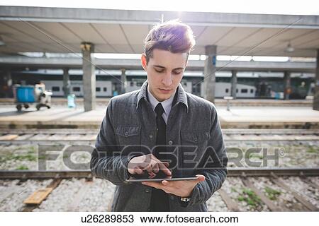 Portrait of young businessman commuter using digital tablet at train station. View Large Photo Image Stock Image - Portrait of young businessman commuter using digital tablet at train station.. Fotosearch