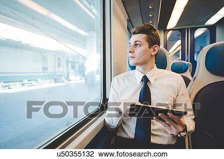 Portrait of young businessman commuter using digital tablet on train. View Large Photo Image Stock Image - Portrait of young businessman commuter using digital tablet on train.. Fotosearch