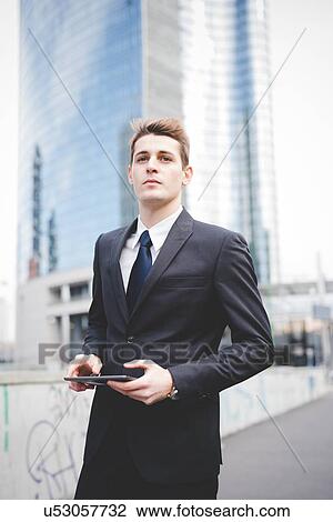 Stock Image - Portrait of young businessman commuter using digital tablet.. Fotosearch