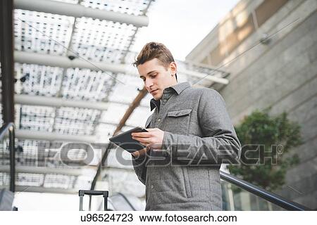 Stock Image - Portrait of young businessman commuter using digital tablet.. Fotosearch