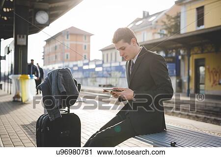 Stock Image - Portrait of young businessman commuter using digital tablet at train station.. Fotosearch