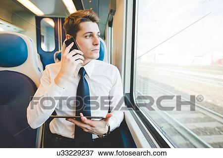 Portrait of young businessman commuter using digital tablet on train. View Large Photo Image Stock Photo - Portrait of young businessman commuter using digital tablet on train.. Fotosearch