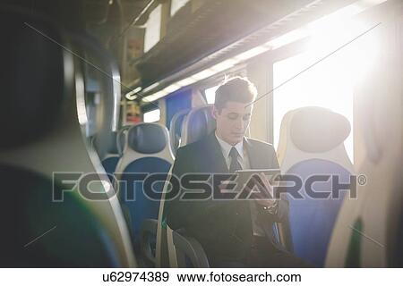 Portrait of young businessman commuter using digital tablet on train. View Large Photo Image Stock Photo - Portrait of young businessman commuter using digital tablet on train.. Fotosearch