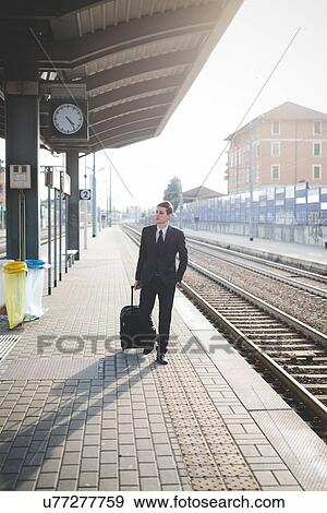Stock Photo - Portrait of young businessman commuter walking along railway platform.. Fotosearch
