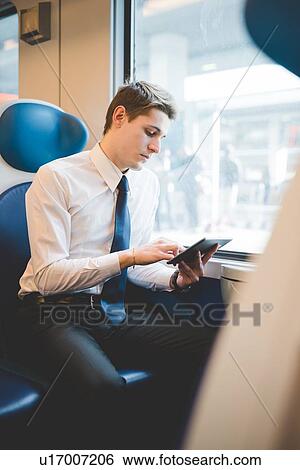 Portrait of young businessman commuter using digital tablet on train. View Large Photo Image Stock Photograph - Portrait of young businessman commuter using digital tablet on train.. Fotosearch