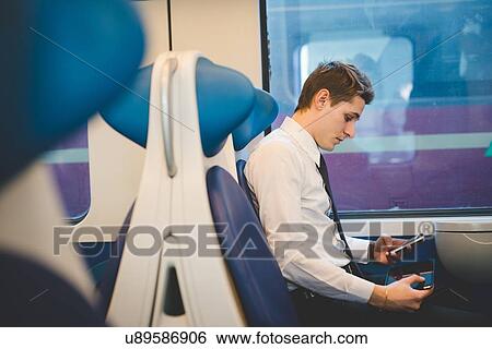 Stock Photograph - Portrait of young businessman commuter using digital tablet on train.. Fotosearch
