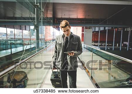 Stock Photography - Portrait of young businessman commuter using digital tablet at train station.. Fotosearch