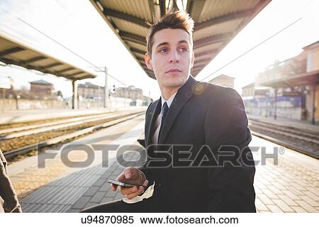 Portrait of young businessman commuter sitting at railway platform. View Large Photo Image Stock Photography - Portrait of young businessman commuter sitting at railway platform.. Fotosearch