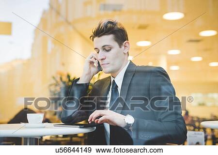 Portrait of young businessman sitting in cafe using digital tablet and mobile phone. View Large Photo Image Stock Photo - Portrait of young businessman sitting in cafe using digital tablet and mobile phone.. Fotosearch