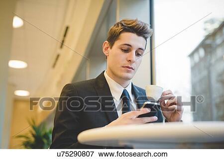 Portrait of young businessman sitting in cafe using digital tablet and mobile phone. View Large Photo Image Stock Photo - Portrait of young businessman sitting in cafe using digital tablet and mobile phone.. Fotosearch