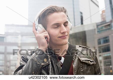 Portrait of young man on street listening to headphones, New York, USA View Large Photo Image Stock Photography - Portrait of young man on street listening to headphones, New York, USA. Fotosearch