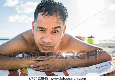 Stock Photo - Portrait of young man sunbathing on Waikiki Beach, Hawaii, USA. Fotosearch