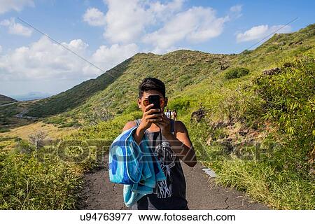 Portrait of young man taking smartphone selfie on Makapuu coast path, Oahu, Hawaii, USA View Large Photo Image Stock Photo - Portrait of young man taking smartphone selfie on Makapuu coast path, Oahu, Hawaii, USA. Fotosearch