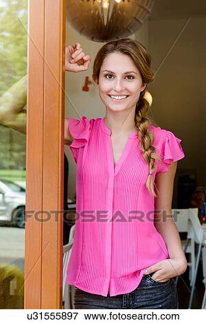 Stock Photo - Portrait of young woman leaning on cafe doorway. Fotosearch