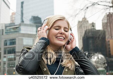 Portrait of young woman on street listening to headphones with eyes closed, New York, USA View Large Photo Image Stock Image - Portrait of young woman on street listening to headphones with eyes closed, New York, USA. Fotosearch