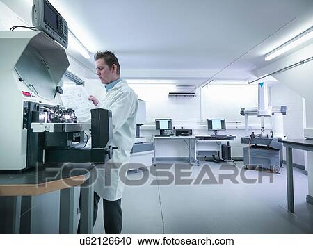 Stock Image - Quality control engineer measuring parts in quality control room. Fotosearch