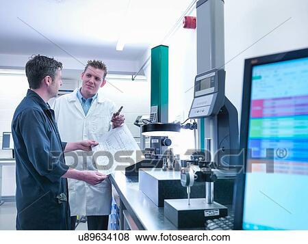 Stock Photo - Quality control engineers in discussion amongst measuring machines. Fotosearch