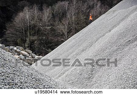 Picture - Quarry worker on gravel mound at quarry. Fotosearch